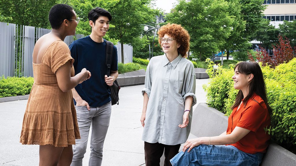 Groupe d'étudiants échangeant à l'extérieur sur un campus, illustrant la diversité et les échanges dans un contexte de formation internationale.