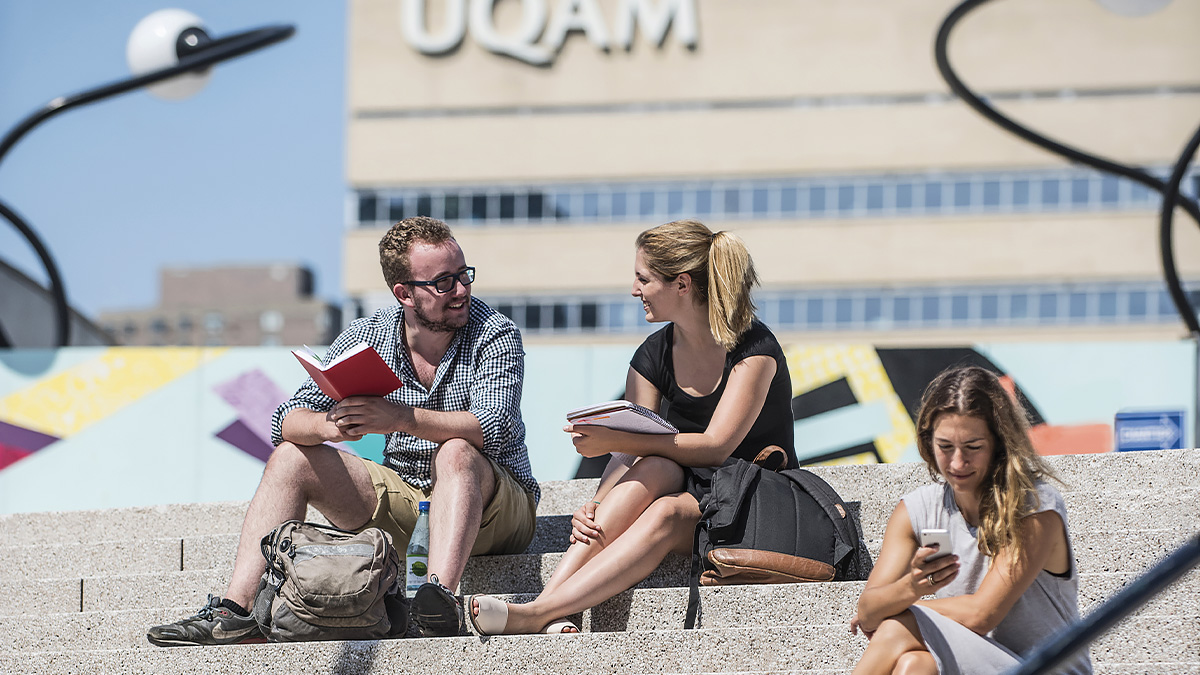 Deux étudiants discutent sur les marches de la Place des Arts. En arrière-plan, on voit le pavillon Président-Kennedy de l’UQAM.