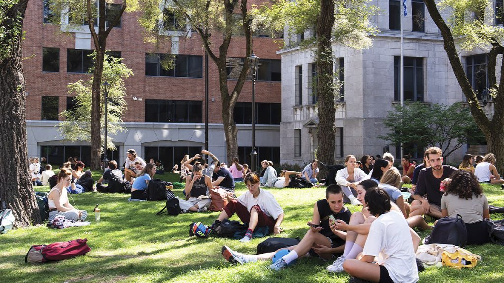 Groupe d'étudiants assis dans l'herbe sur la Place Pasteur.